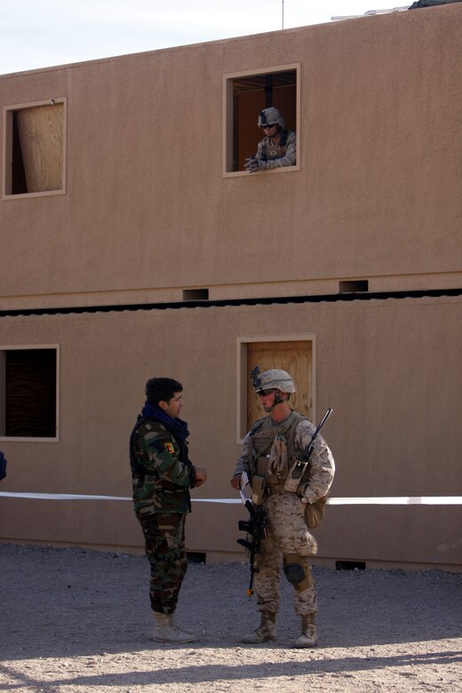 Sgt. Joshua P. Arcindo, a mortarman with Police Mentor Team 2, 3rd Battalion, 3rd Marine Regiment, based out of Marine Corps Base Kaneohe Bay, Hawaii, talks with a mock Afghan policeman at Combat Center Range 220 while another Marine from PMT-2 keeps watch in the building above March 16.